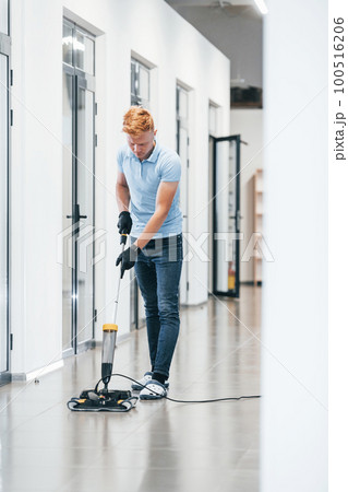 Young man works in the modern office. Uses vacuum cleaner Young man works in the modern office. Uses vacuum cleaner 100516206