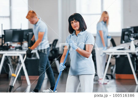 Group of workers clean modern office together at daytime Group of workers clean modern office together at daytime 100516386