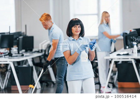Group of workers clean modern office together at daytime 100516414