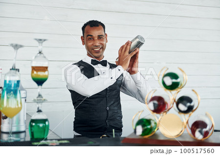 At the bar. Black waiter in formal clothes is at his work outdoors at sunny daytime 100517560