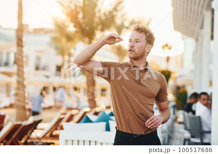 Bright sunshine. Young man is outdoors at sunny daytime. Concept of vacation 100517686