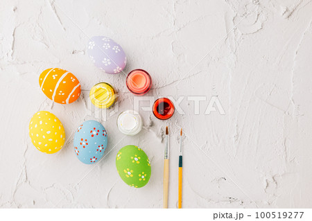 Easter Day Concept. colored multi-colored and paints brush painting easter eggs, colorful paints and paint brushes isolated on white cement background with copy space for text Easter Day Concept. colored multi-colored and paints brush painting easter eggs, colorful paints and paint brushes isolated on white cement background with copy space for text 100519277