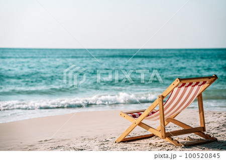 Chaise lounge on the sea sand on the coast of the azure sea and against the blue sky, the concept of relaxation on a tropical island 100520845