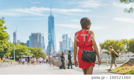 New York city life. Woman walking by view of Manhattan skyline American people walking enjoying Manhattan by the Hudson river side on perfect summer day. NYC cityscape. 100521360