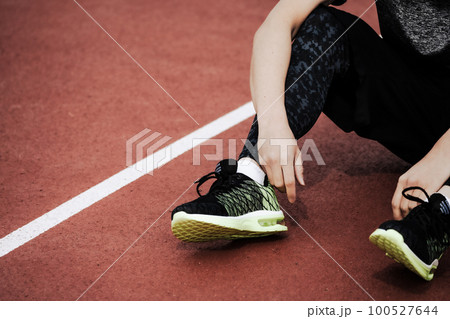 陸上競技場のトラックで座りこむフィニッシュ後のランナー 100527644