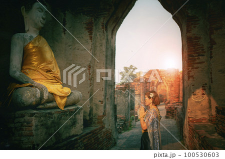 woman wearing thai tradition suit praying to old buddha statue in old temple at ayutthaya one of world heritage site of unesco thailand 100530603