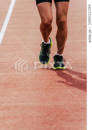 陸上競技のトラックの直線を走る男性ランナー 100532394