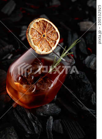 Old-fashioned cocktail with whiskey, ice, orange, and rosemary. 100532925