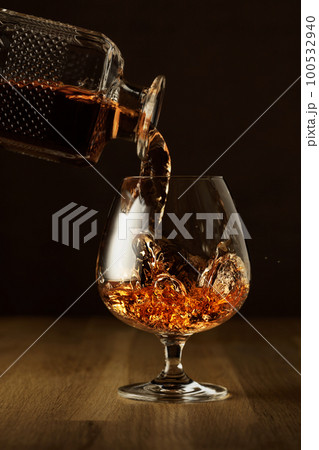 Brandy is poured into a snifter glass. 100532940