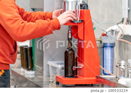 capping beer bottles in a brewery 100533224