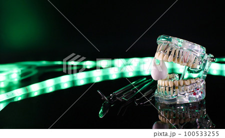 Dental tools and model of teeth on a neon background. Dental care concept. Invisible braces Dental tools and model of teeth on a neon background. Dental care concept. Invisible braces 100533255