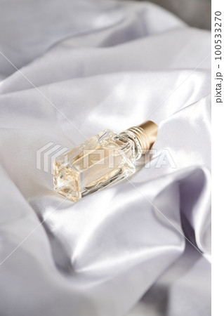 Top view of glass jar with cologne in soft tissue folds. 100533270