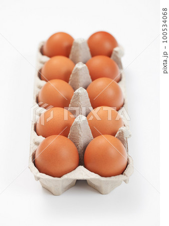 Raw brown organic eggs in paper tray on white with yolk inside Raw brown organic eggs in paper tray on white with yolk inside 100534068