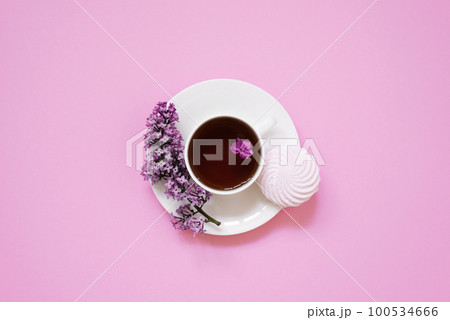 Tea cup with marshmallow dessert and lilac flowers on a pink background. Tea cup with marshmallow dessert and lilac flowers on a pink background. 100534666