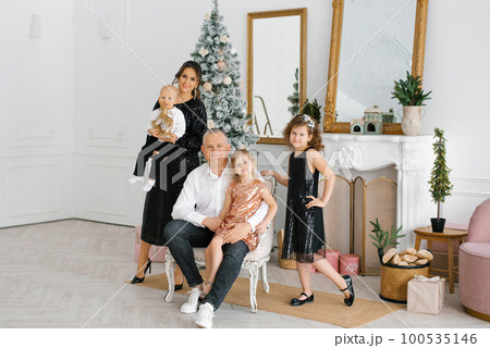A stylish beautiful large family celebrates Christmas and New Year in the living room in their house near the Christmas tree 100535146