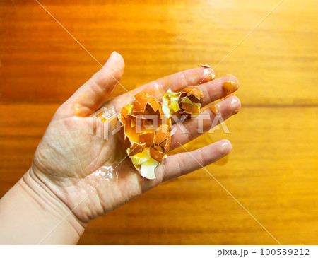 Raw smashed egg in a hand. 100539212