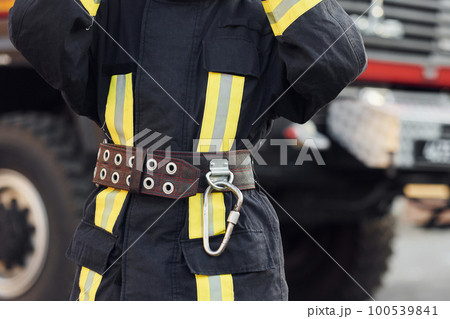 Female firefighter in protective uniform standing near truck Female firefighter in protective uniform standing near truck 100539841