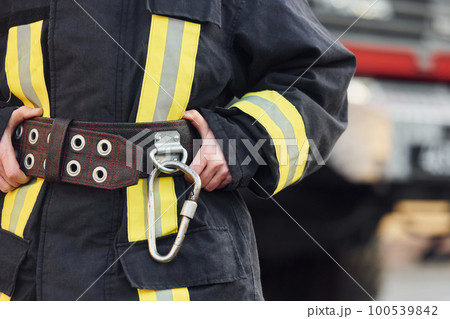 Female firefighter in protective uniform standing near truck 100539842