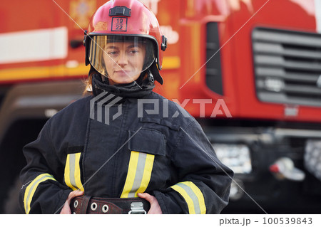Female firefighter in protective uniform standing near truck 100539843
