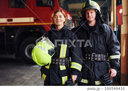 Male and female firefighters in protective uniform standing together 100540410