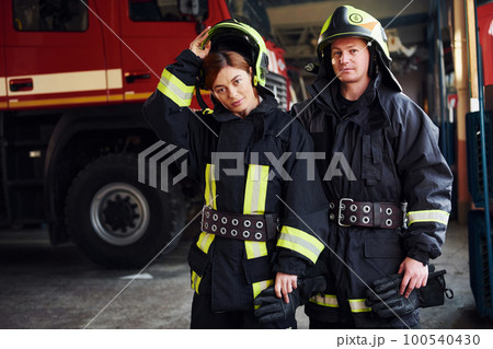 Male and female firefighters in protective uniform standing together Male and female firefighters in protective uniform standing together 100540430