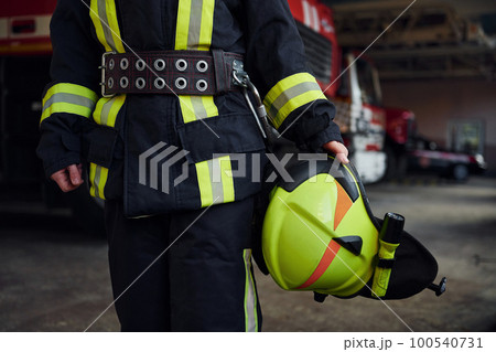 Close up view. Female firefighter in protective uniform standing near truck Close up view. Female firefighter in protective uniform standing near truck 100540731