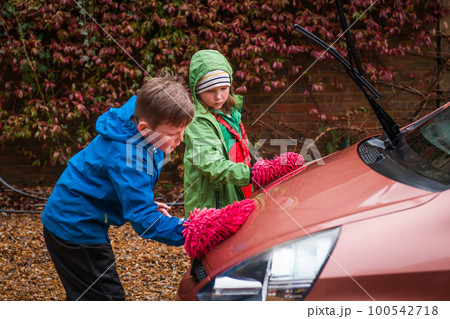 Boy and girl are washing car. Happy time together. Save money and helping family. Children working in one team. Job for school kids. 100542718