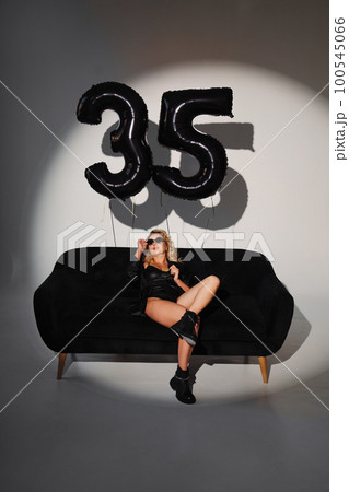 a sexy blonde in a black on the couch. balloons of numbers thirty-five 100545066