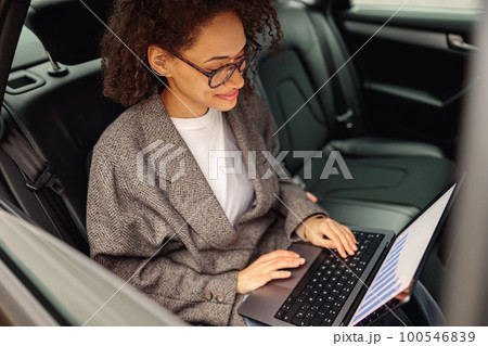 Smiling businesswoman manager working on laptop sitting car leather backseat on the way to office 100546839