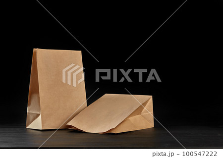 Eco friendly disposable tableware standing on dark surface against black background. Biodegradable craft dishes. Recycling concept. Close-up shot. 100547222