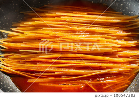 暗殺者のパスタ作り　トマトだしを加えていく 100547282