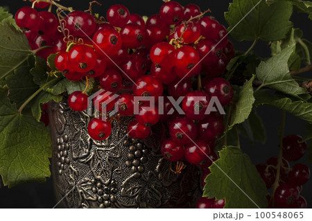 Red currant berries in a silver glass close-up. 100548065
