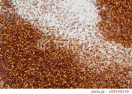 Golden sequins are scattered on a white background. 100549239
