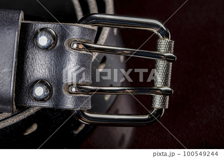 Black leather belt on a dark background. Leather products. 100549244