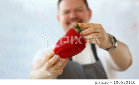 Smiling male cook holding red peppers closeup 100550110