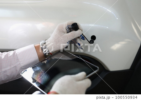 Auto mechanic holds tablet and car tube on white auto Auto mechanic holds tablet and car tube on white auto 100550934