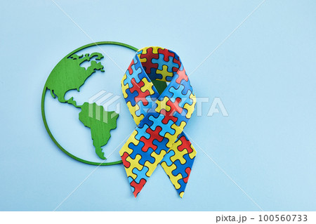 World Autism awareness and pride day or month with Puzzle pattern ribbon on blue background 100560733