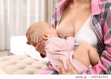 Young woman breastfeeding her little baby at home 100562301