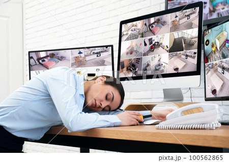 Female security guard sleeping near monitors at workplace 100562865