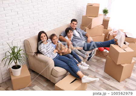 Happy family resting in room with cardboard boxes on moving day Happy family resting in room with cardboard boxes on moving day 100562979