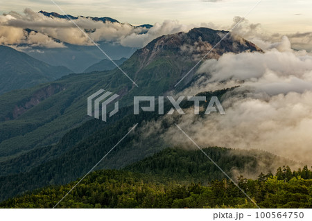 夕暮れの北アルプス・西穂高岳稜線から雲流れる焼岳の眺め 100564750
