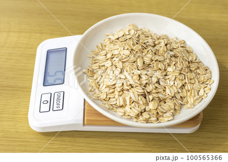 デジタルキッチンスケールでオートミール（オーツ麦）を量るイメージ 100565366