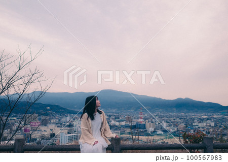 朝日を浴び街をバックに佇む女性の写真 朝日を浴び街をバックに佇む女性の写真 100567983