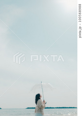 海辺に傘を持って佇む女性の写真 100568988
