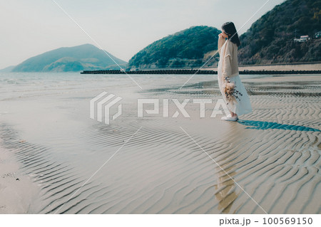 海辺にドライフラワーを持って佇む女性の写真 海辺にドライフラワーを持って佇む女性の写真 100569150