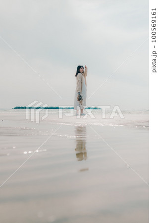 海辺にドライフラワーを持って佇む女性の写真 100569161