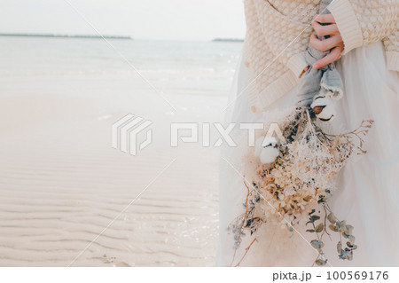 海辺にドライフラワーを持って佇む女性の写真 海辺にドライフラワーを持って佇む女性の写真 100569176