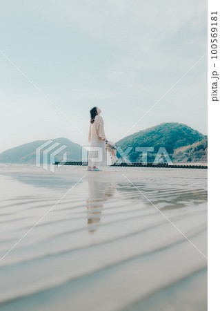 海辺にドライフラワーを持って佇む女性の写真 海辺にドライフラワーを持って佇む女性の写真 100569181