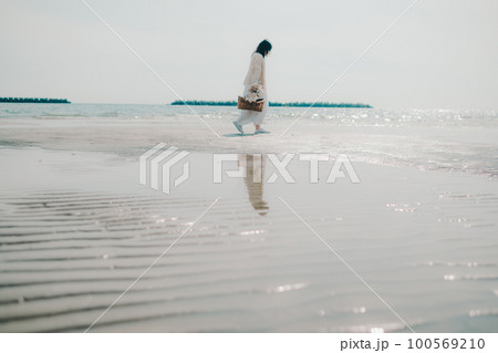 海辺にドライフラワーとカゴを持って佇む女性の写真 100569210