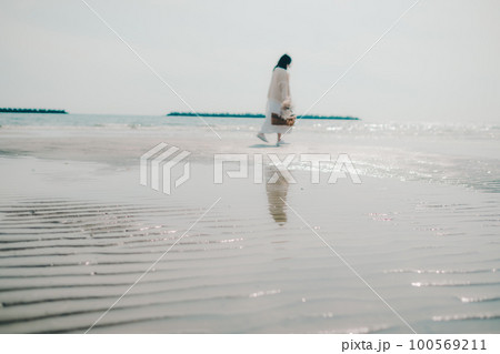 海辺にドライフラワーとカゴを持って佇む女性の写真 100569211